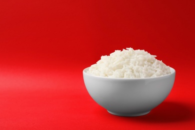 Bowl of tasty cooked rice on color background. Space for text