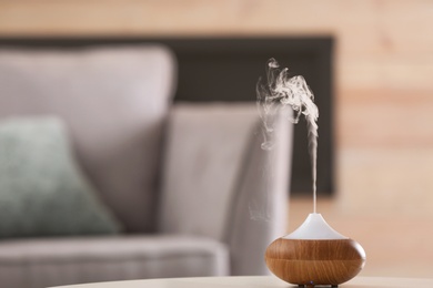 Photo of Aroma oil diffuser lamp on table against blurred background