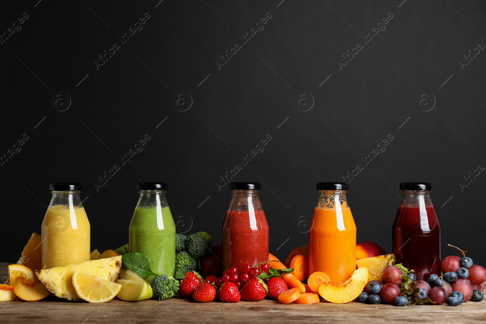 Photo of Bottles of delicious juices and fresh fruits on wooden table