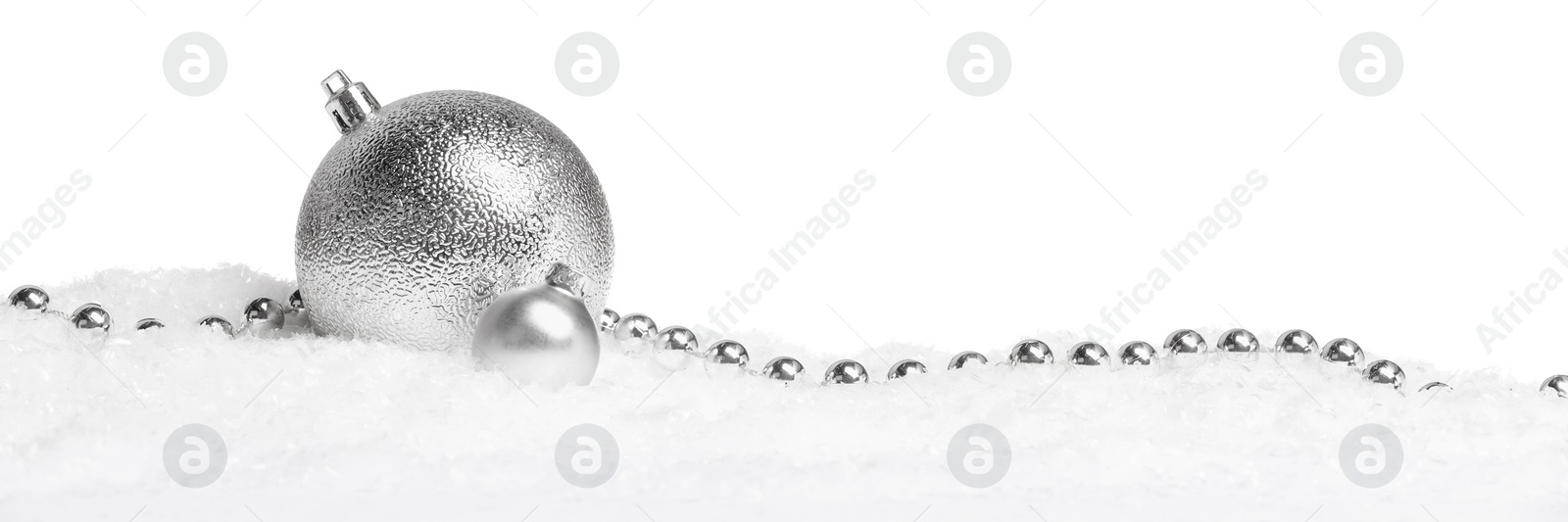 Photo of Beautiful silver Christmas balls and garland on snow against white background