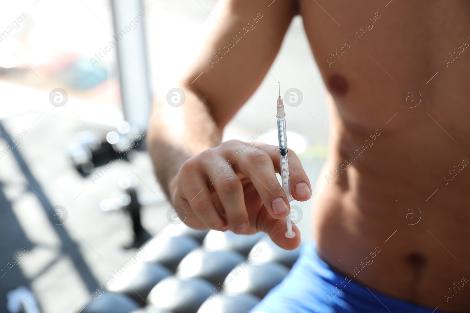 Photo of Athletic man with syringe indoors, closeup. Doping concept