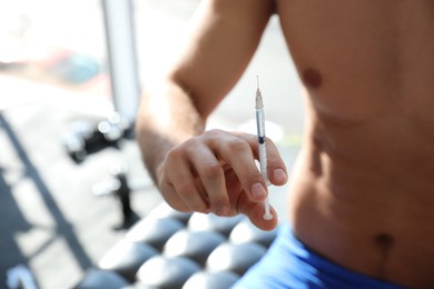 Photo of Athletic man with syringe indoors, closeup. Doping concept