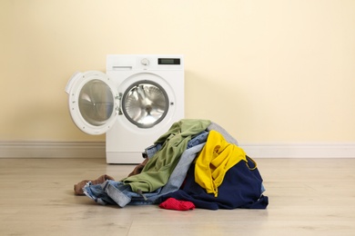 Pile of dirty laundry near washing machine indoors