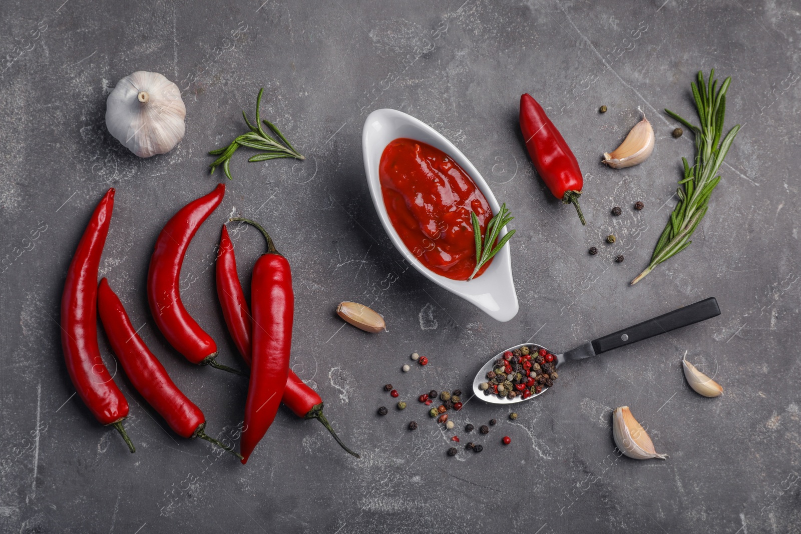 Photo of Flat lay composition with chili sauce and different spices on dark background