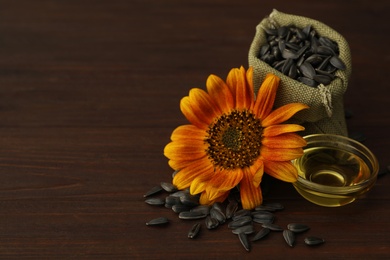 Photo of Sunflower, oil and seeds on wooden table, space for text