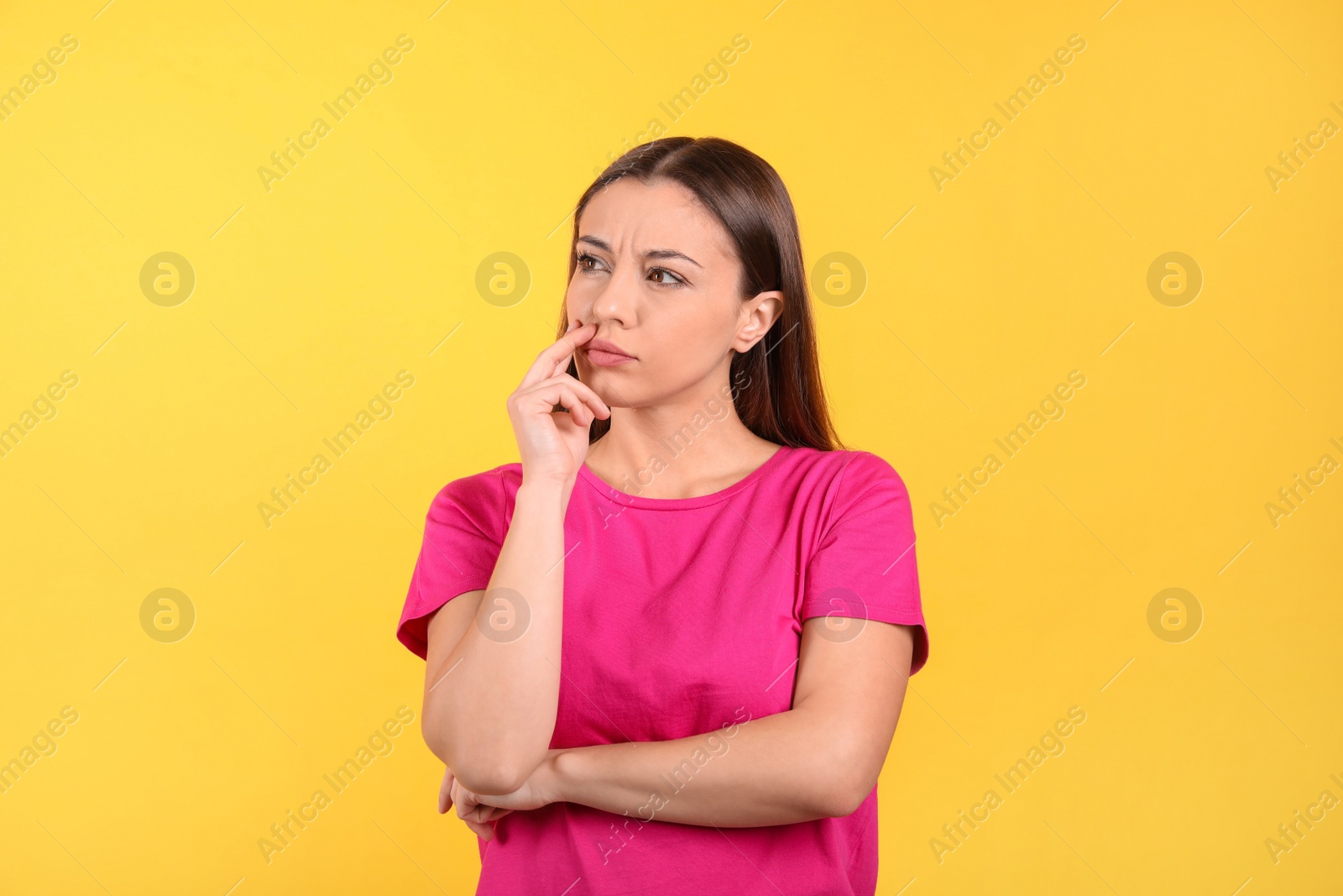 Photo of Portrait of stressed young woman on yellow background