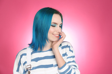 Young woman with bright dyed hair on pink background