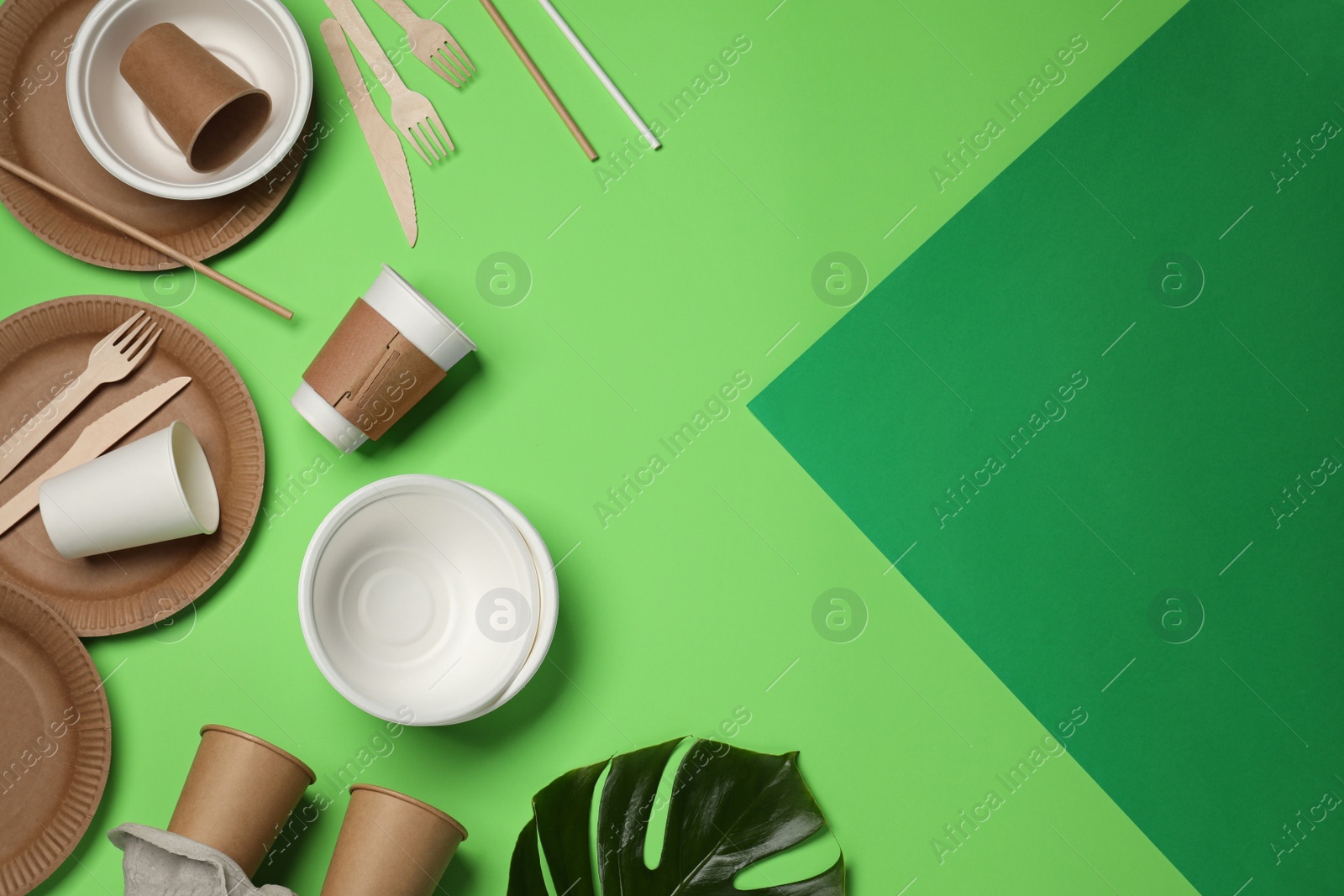 Photo of Flat lay composition with disposable tableware on green background, space for text