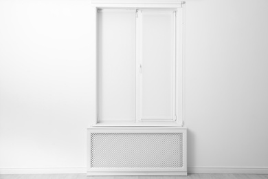Photo of Modern window with closed Roman blinds in empty room