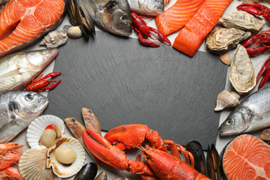 Fresh fish and different seafood on grey table, flat lay. Space for text