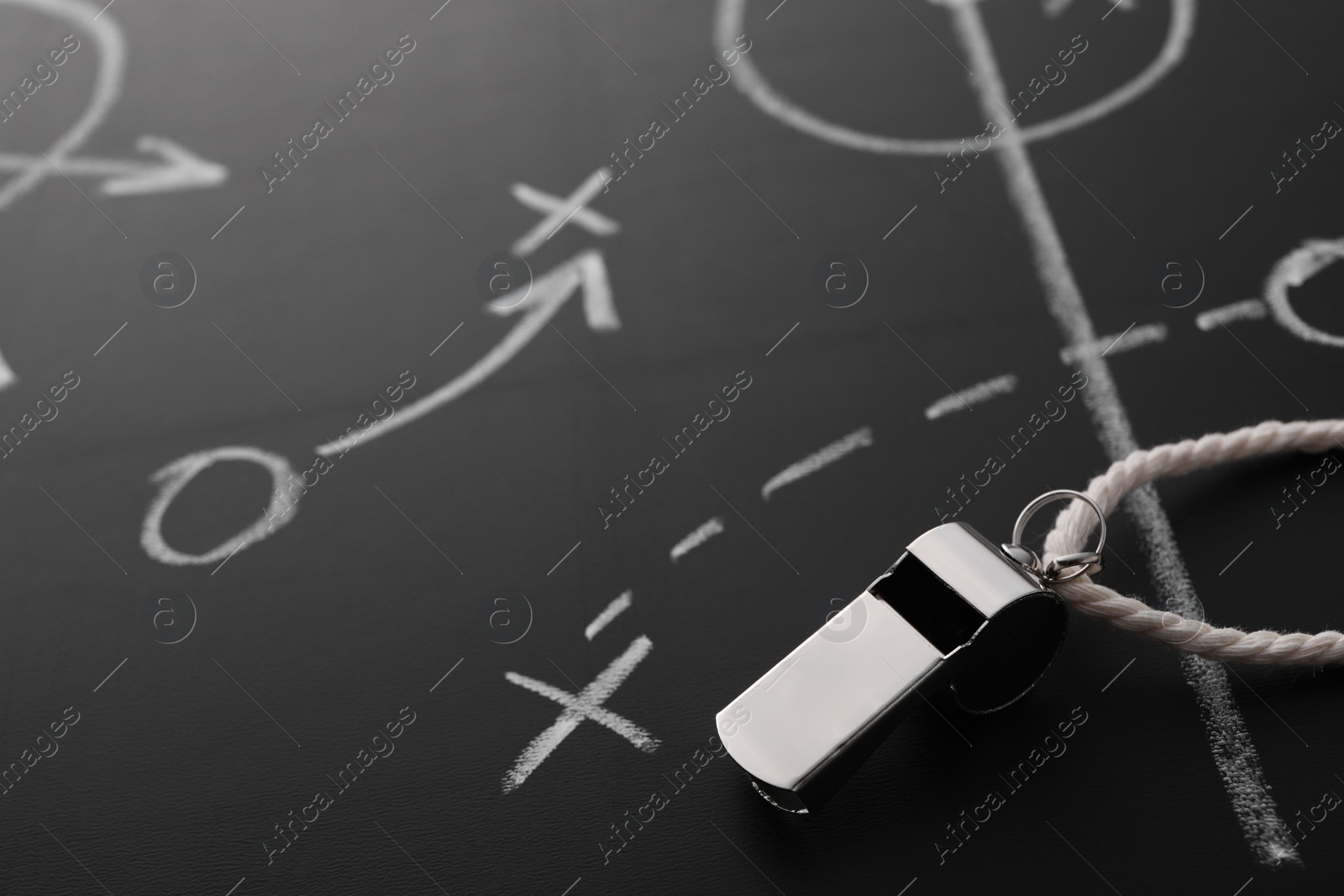 Photo of Referee whistle on chalkboard with game scheme, closeup