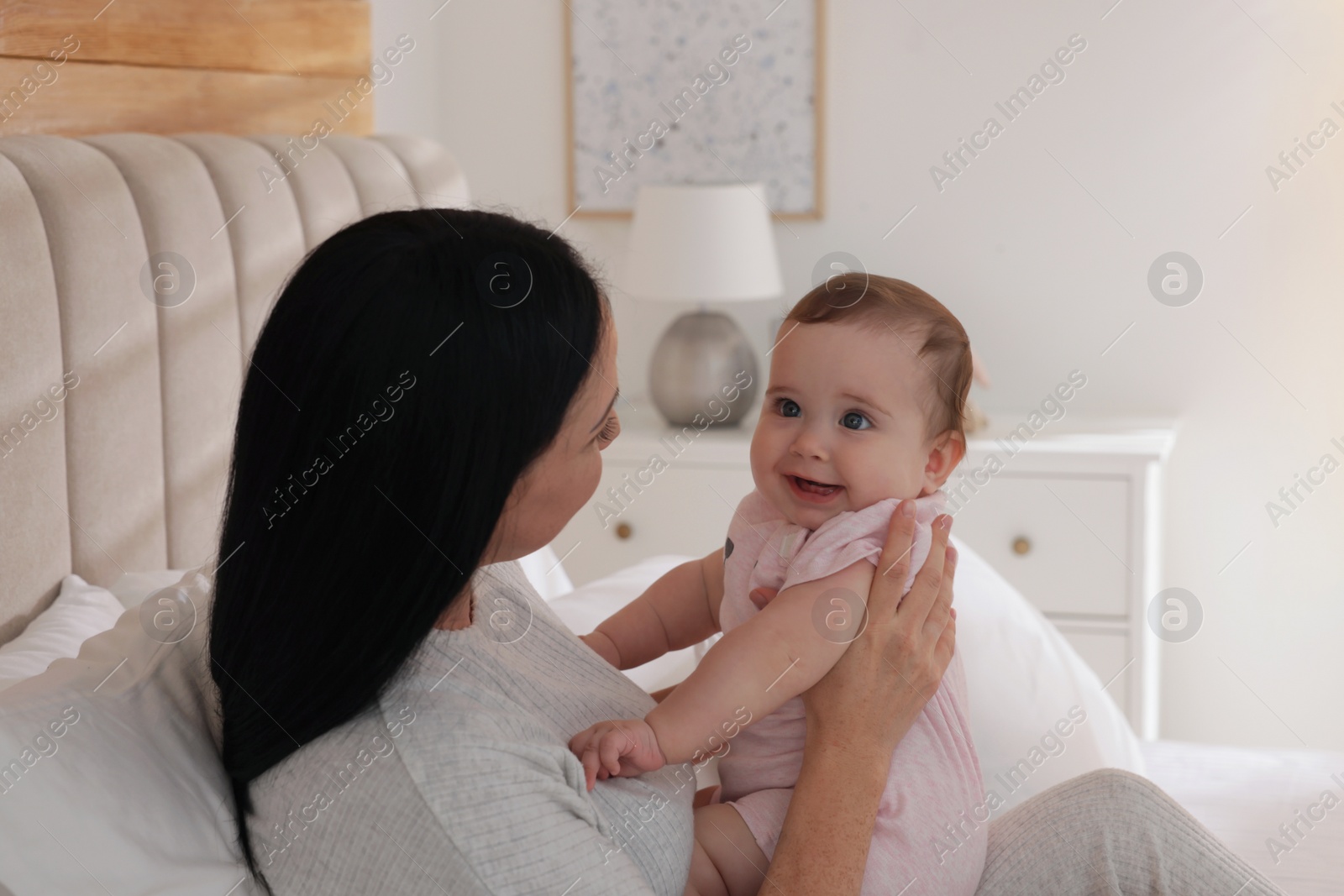 Photo of Happy woman with her little baby on bed at home