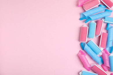 Photo of Different hair curlers on pink background, flat lay. Space for text