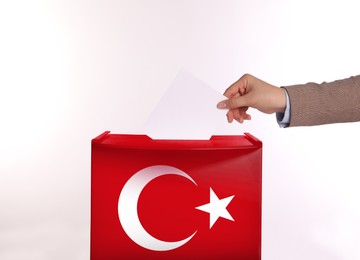 Image of Woman putting her vote into ballot box decorated with flag of Turkey against white background, closeup