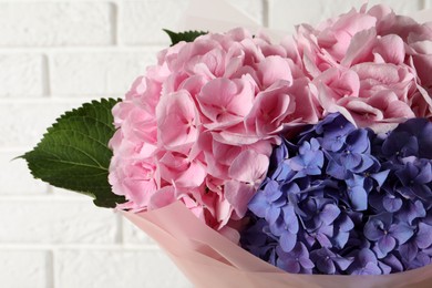 Bouquet of beautiful hortensia flowers near white brick wall, closeup