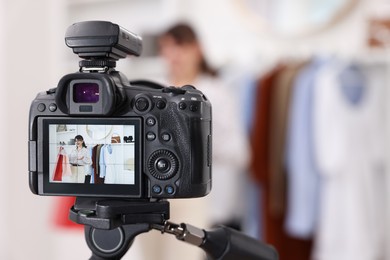 Photo of Fashion blogger with shopping bags recording video at home, focus on camera