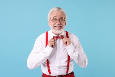 Photo of Portrait of stylish grandpa with glasses and bowtie on light blue background