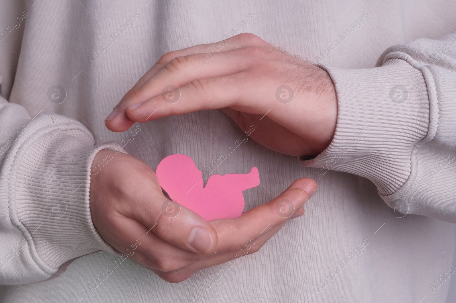 Photo of Female health. Man holding newborn paper figure, closeup