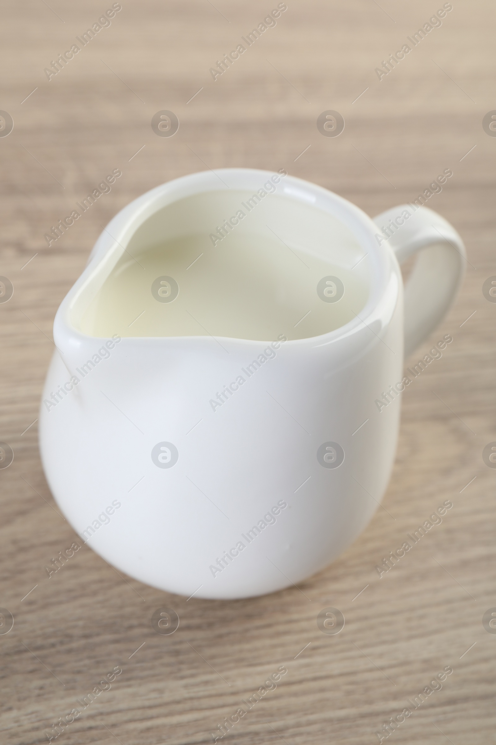 Photo of Jug of fresh milk isolated on wooden table, closeup