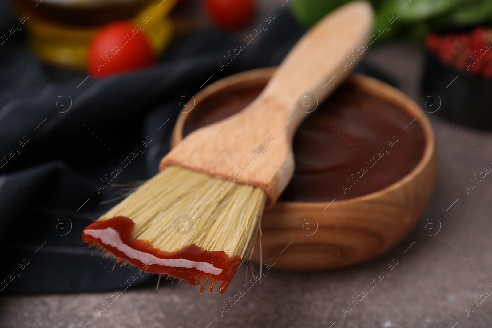 Photo of Marinade in bowl and basting brush on brown table, selective focus