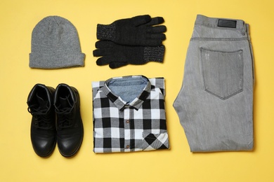 Photo of Flat lay composition with winter clothes and boots on yellow background