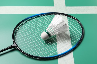 Photo of Feather badminton shuttlecock and racket on green table, closeup