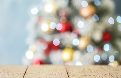 Photo of Empty white wooden table and blurred fir tree with Christmas lights on background, bokeh effect. Space for design