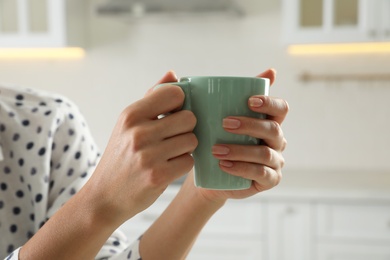 Woman with green cup at home, closeup