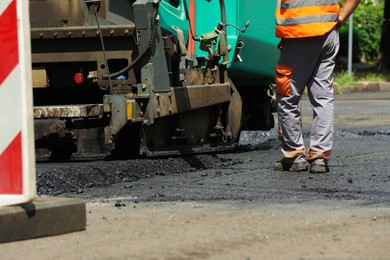 Photo of Worker near asphalt paver, closeup. Road repair