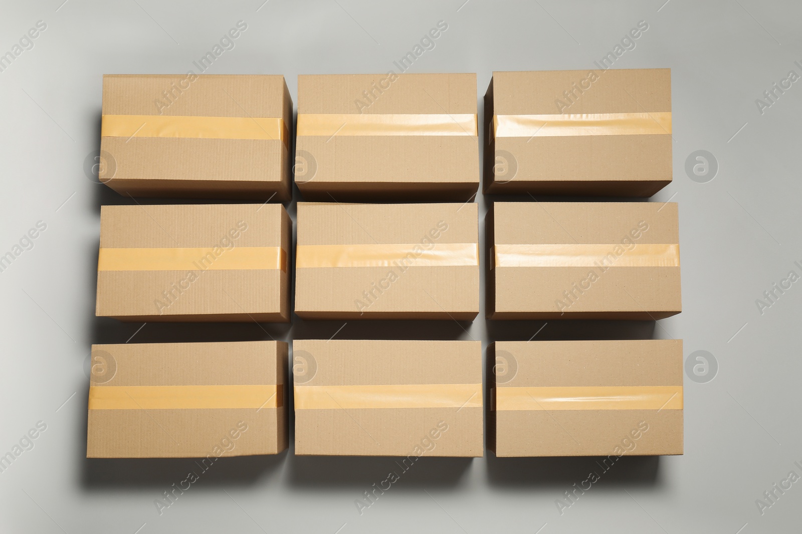 Photo of Many closed cardboard boxes with tape on light grey background, flat lay