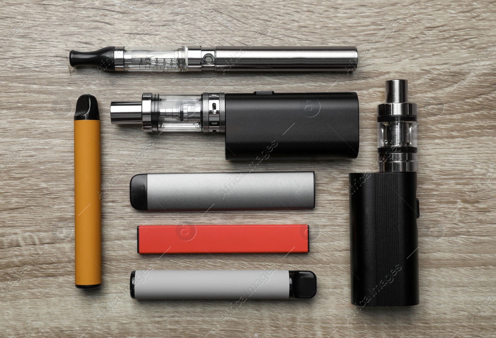 Photo of Different electronic cigarettes on wooden background, flat lay