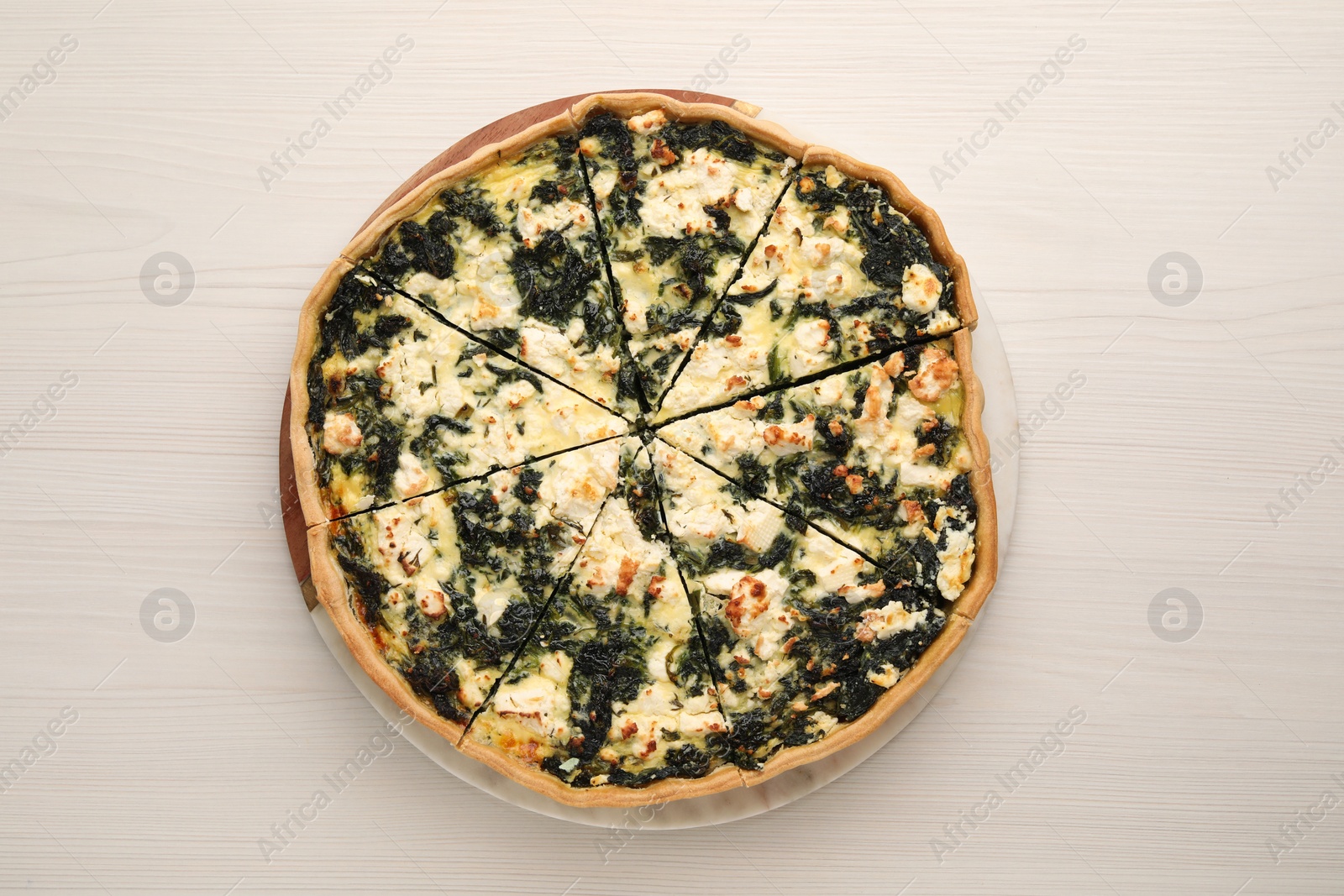 Photo of Delicious homemade spinach quiche on white wooden table, top view