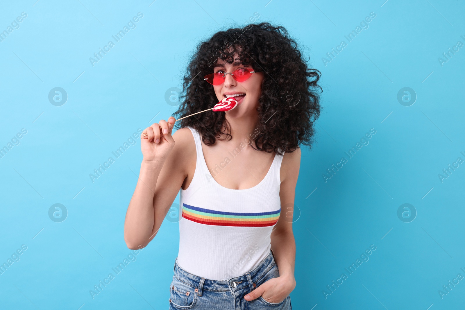 Photo of Beautiful woman in sunglasses with lollipop on light blue background