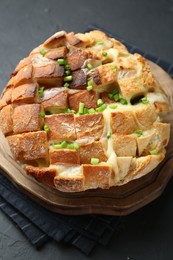 Photo of Freshly baked bread with tofu cheese and green onions on black table