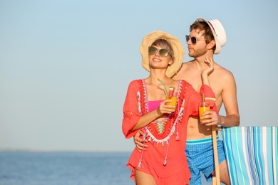 Photo of Young couple with exotic cocktails on beach. Space for text