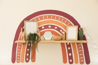 Photo of Wooden shelf with interior decor and rainbow on white wall indoors