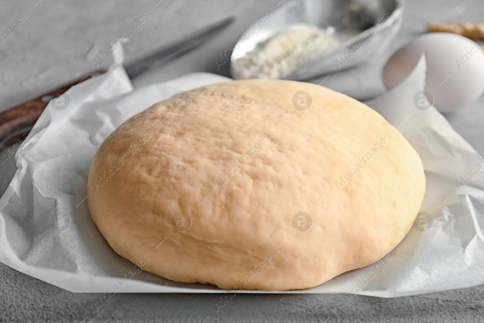 Photo of Fresh raw dough on parchment paper, closeup