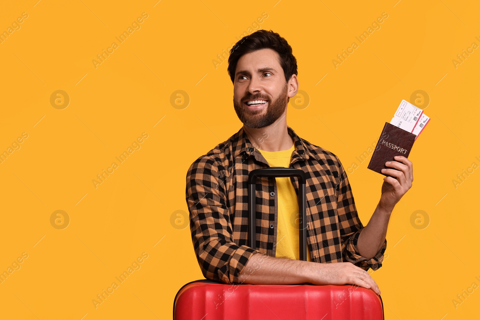 Photo of Smiling man with passport, tickets and suitcase on yellow background. Space for text