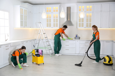 Team of professional janitors cleaning modern kitchen