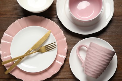 Photo of Beautiful ceramic dishware, cutlery and cup on wooden table, flat lay