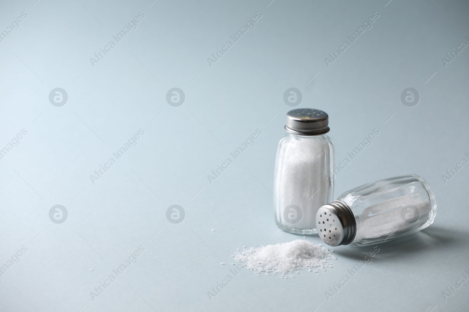 Photo of Natural salt in shakers on color background, space for text