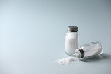 Photo of Natural salt in shakers on color background, space for text