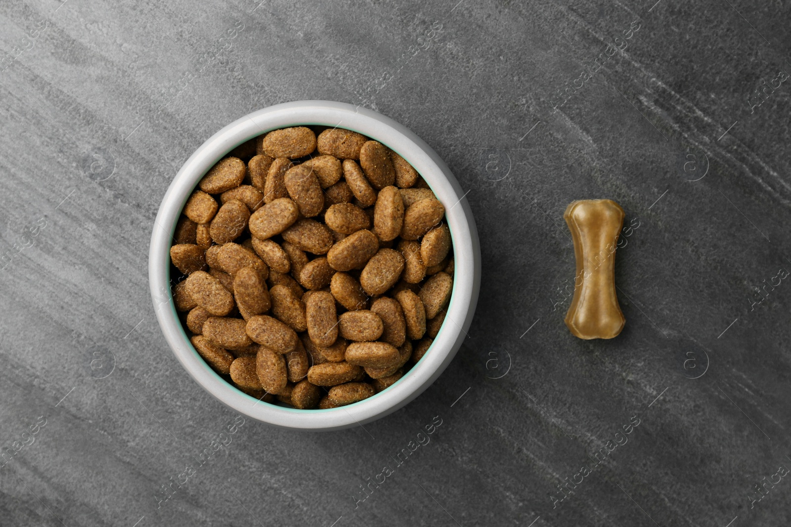 Photo of Dry dog food and treat (chew bone) on textured background, flat lay