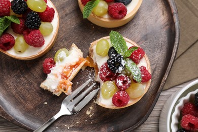 Delicious tartlets with berries on wooden table, flat lay