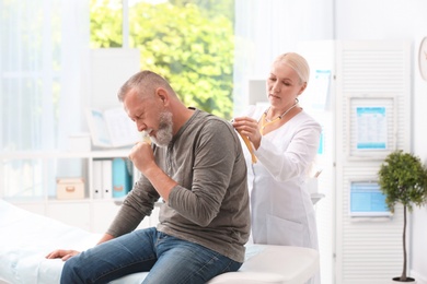 Doctor examining coughing mature man at clinic