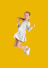 Image of Happy cute girl jumping on golden background