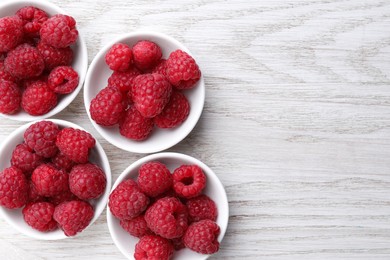 Photo of Tasty ripe raspberries on white wooden table, flat lay. Space for text