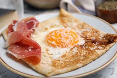 Photo of Delicious crepe with egg on table, closeup. Breton galette