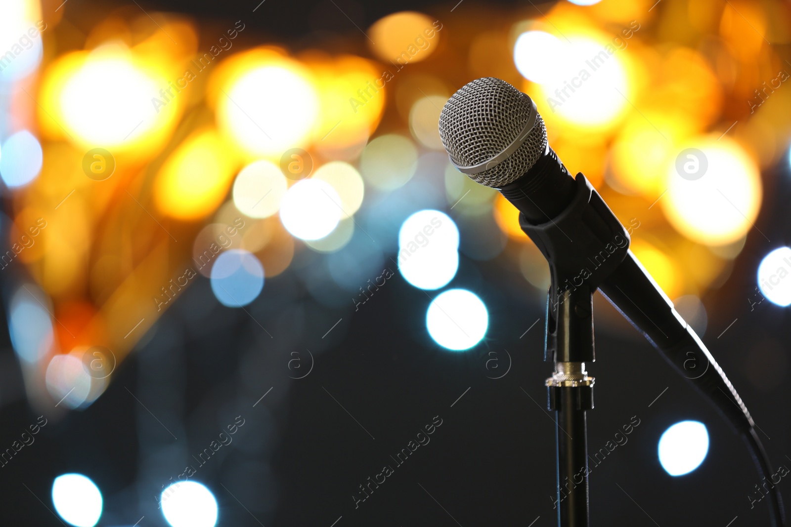 Photo of Microphone against festive lights, space for text. Musical equipment