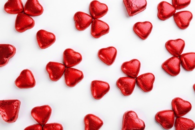 Heart shaped chocolate candies in red foil on white background, top view